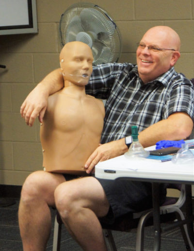 Photo of a man holding a training manikin