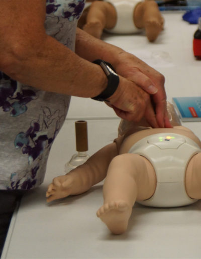 Picture of a student administering CPR compressions to an infant manikin