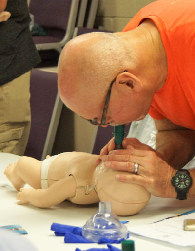 Image of student administering infant CPR - breaths into the infant manikin.
